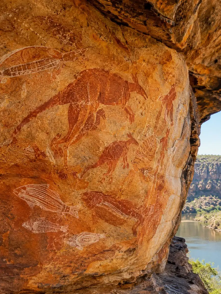 Rote Ocker-Aborigines-Felsmalerei an einem Sandsteinvorsprung neben einer Fluss-Schlucht